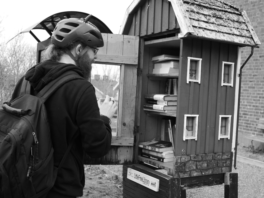 Herb kollar på böckerna i Tollereds mikrobibliotek, framför det riktiga biblioteket